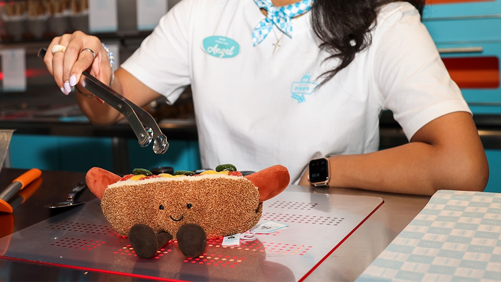 La figura de peluche frutal de Jellycat Diner se presenta con un menú